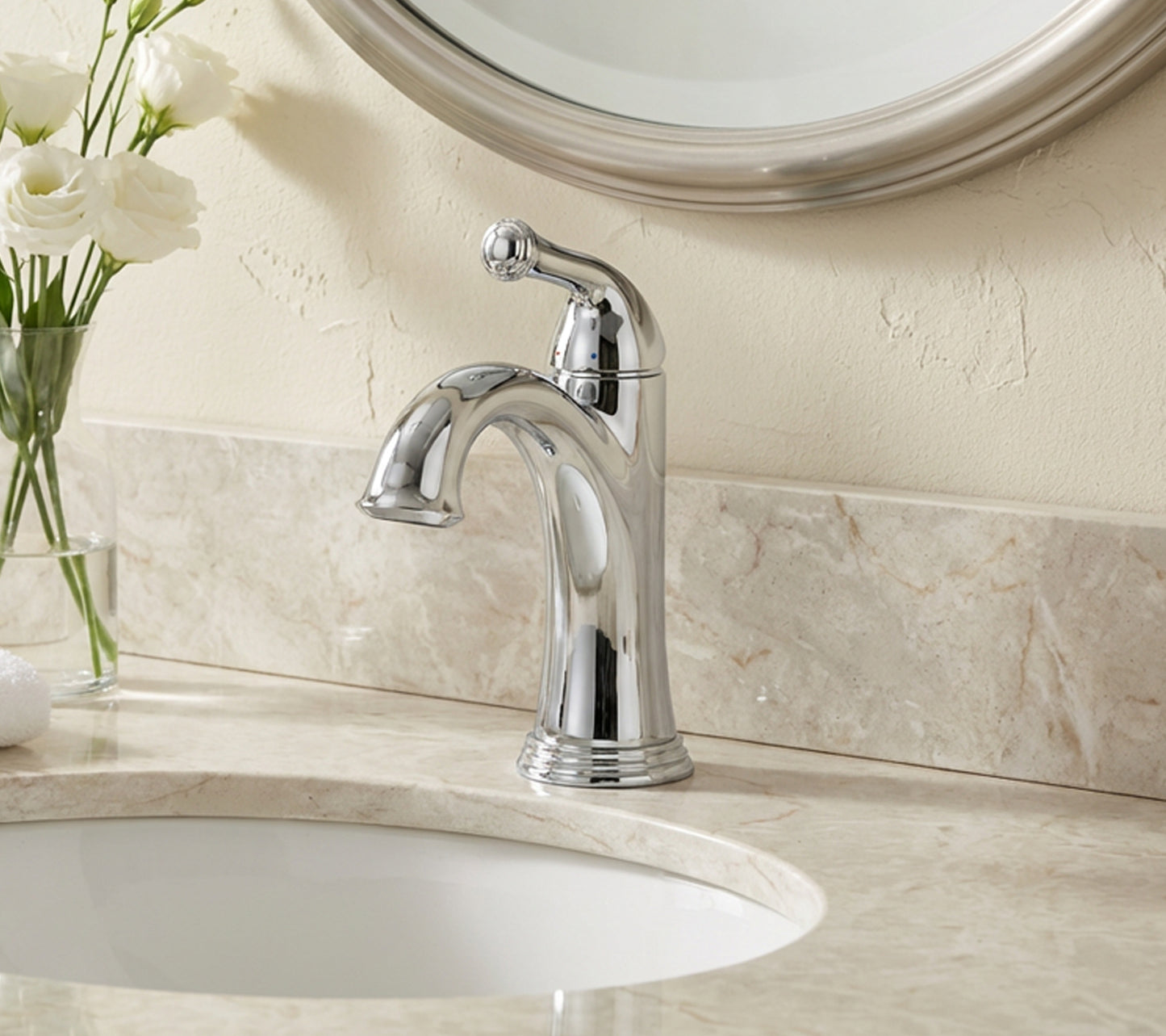 Chrome faucet on a bathroom sink with a mirror and flowers in the background