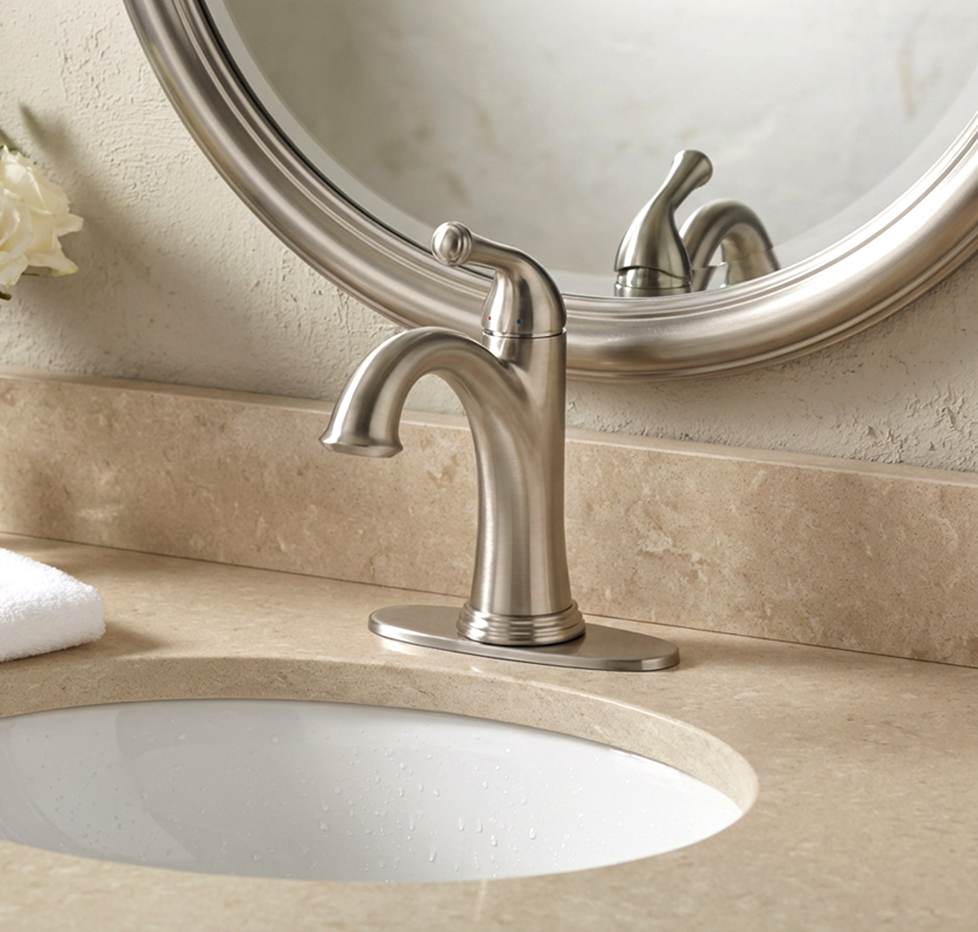 Bathroom sink with silver faucet and round mirror above