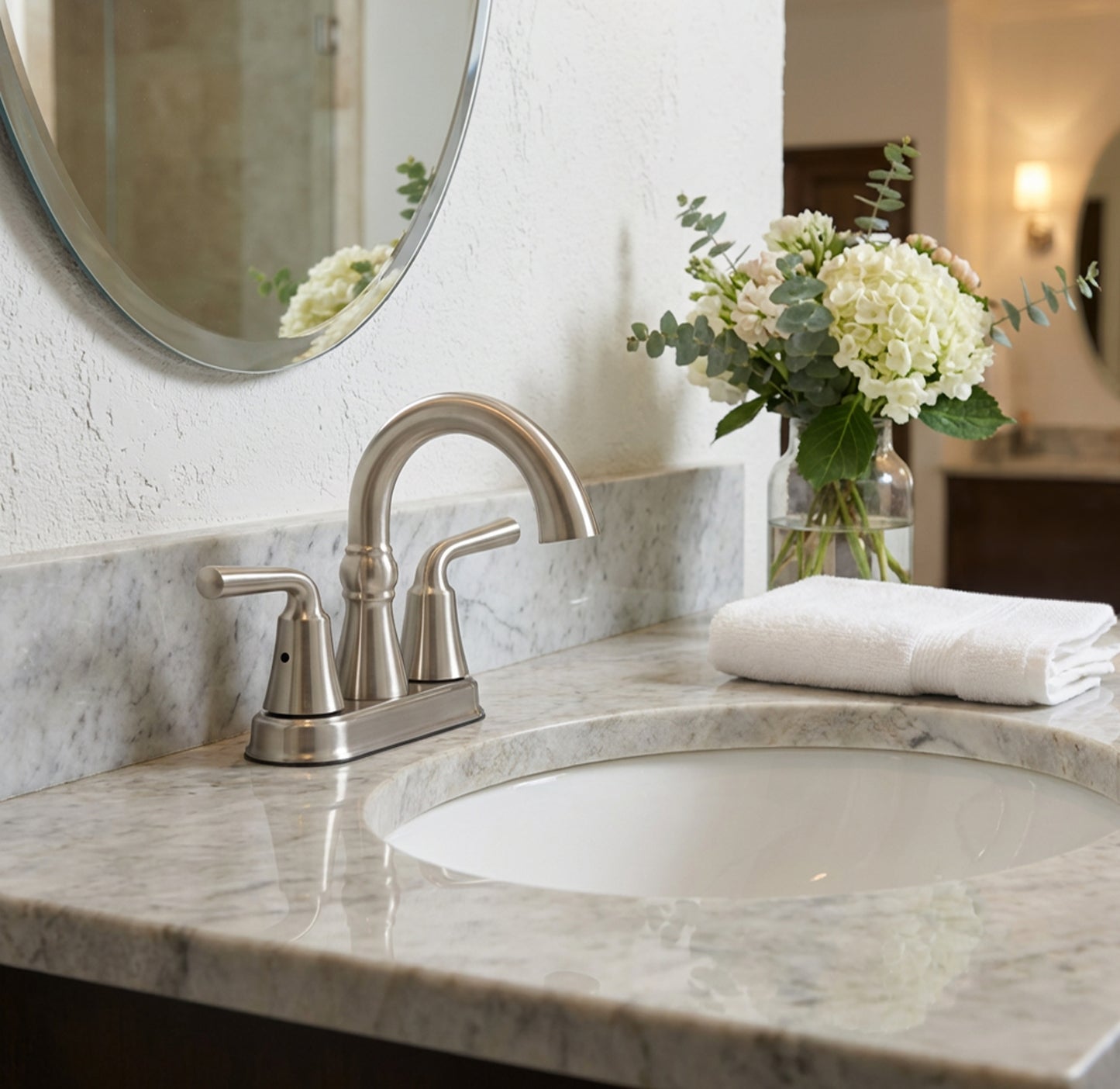 Bathroom vanity with marble countertop, sink, and decorative flowers.