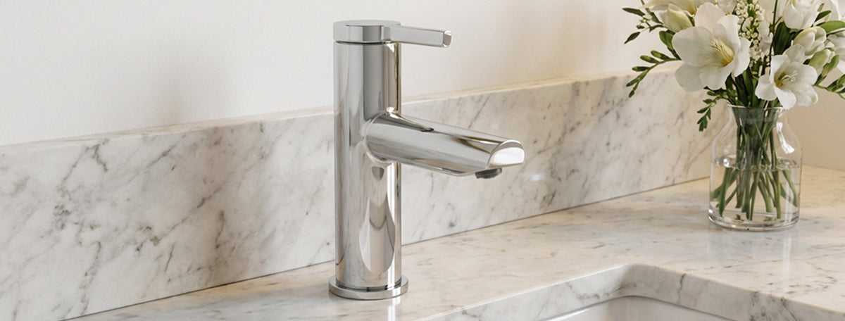 Modern silver faucet on a marble countertop with flowers in the background